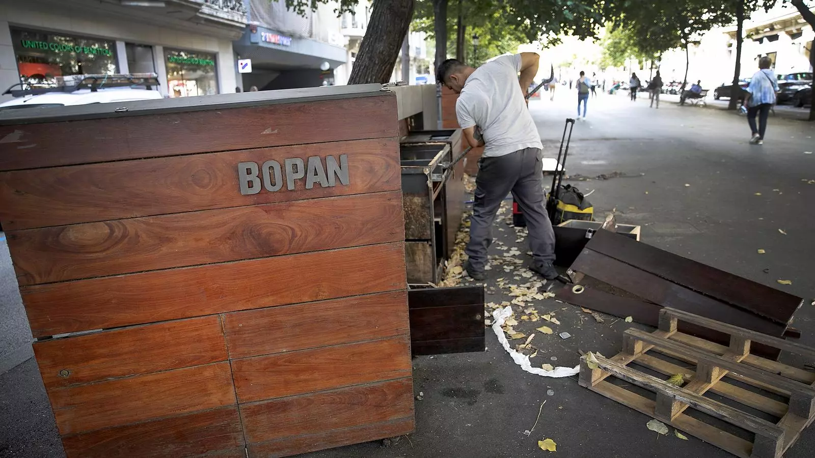 Un home desmuntant el taulell del Bopan abandonat a la Rambla de Catalunya.