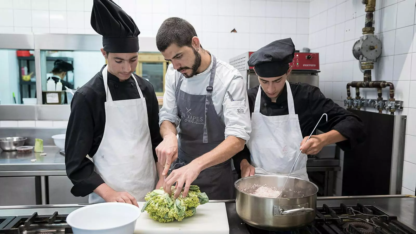 El cap de cuina del Can Xapes, Lluc Quintana, amb el Brahim i l’Ismael als fogons del restaurant.