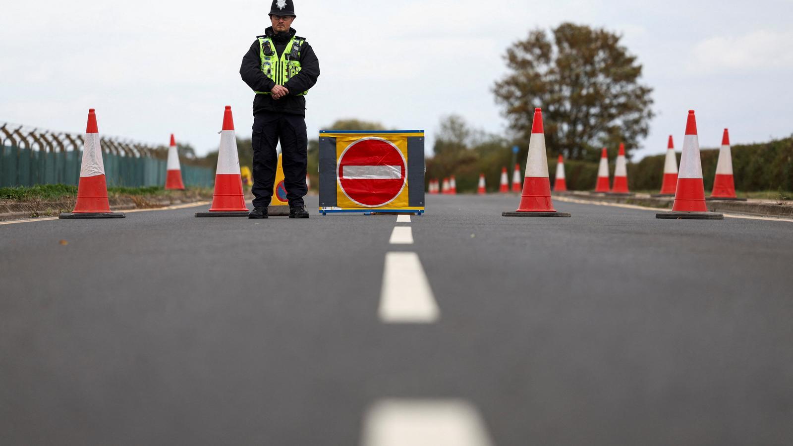 Un agente de policía vigila un corte de carretera a las afueras del perímetro de la base aérea de la RAF Fairford, después de que la policía declarara un incidente grave en la base a raíz de la detención, este domingo, de cinco hombres sospechosos de un posible ataque terrorista.