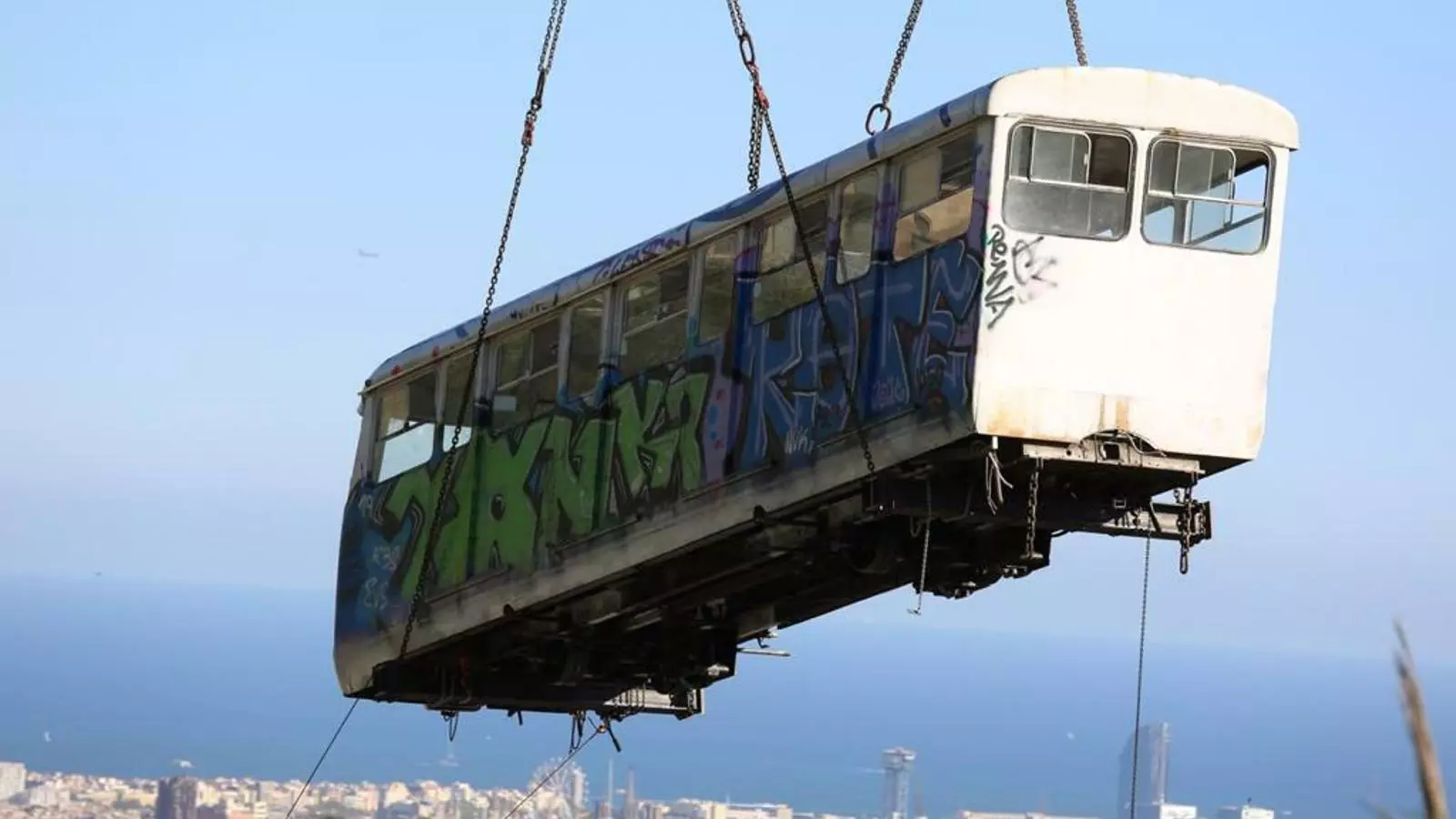 Un dels antics combois del funicular del Tibidabo suspès davant de Barcelona