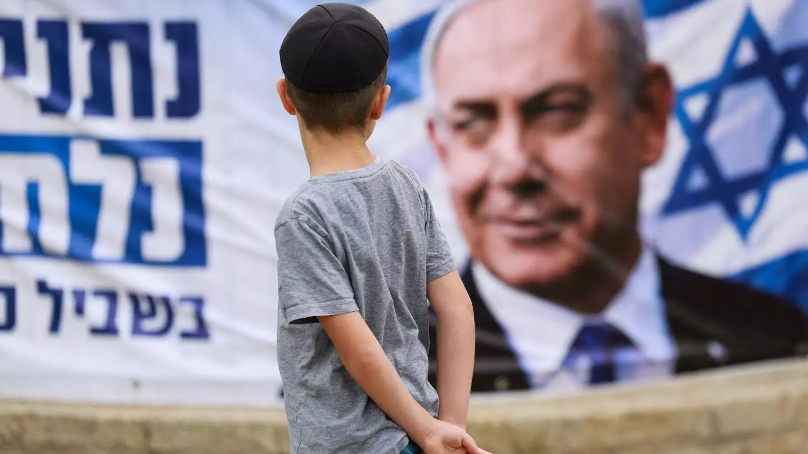 Un infant contempla un cartell electoral del primer ministre israelià, Benjamin Netanyahu.