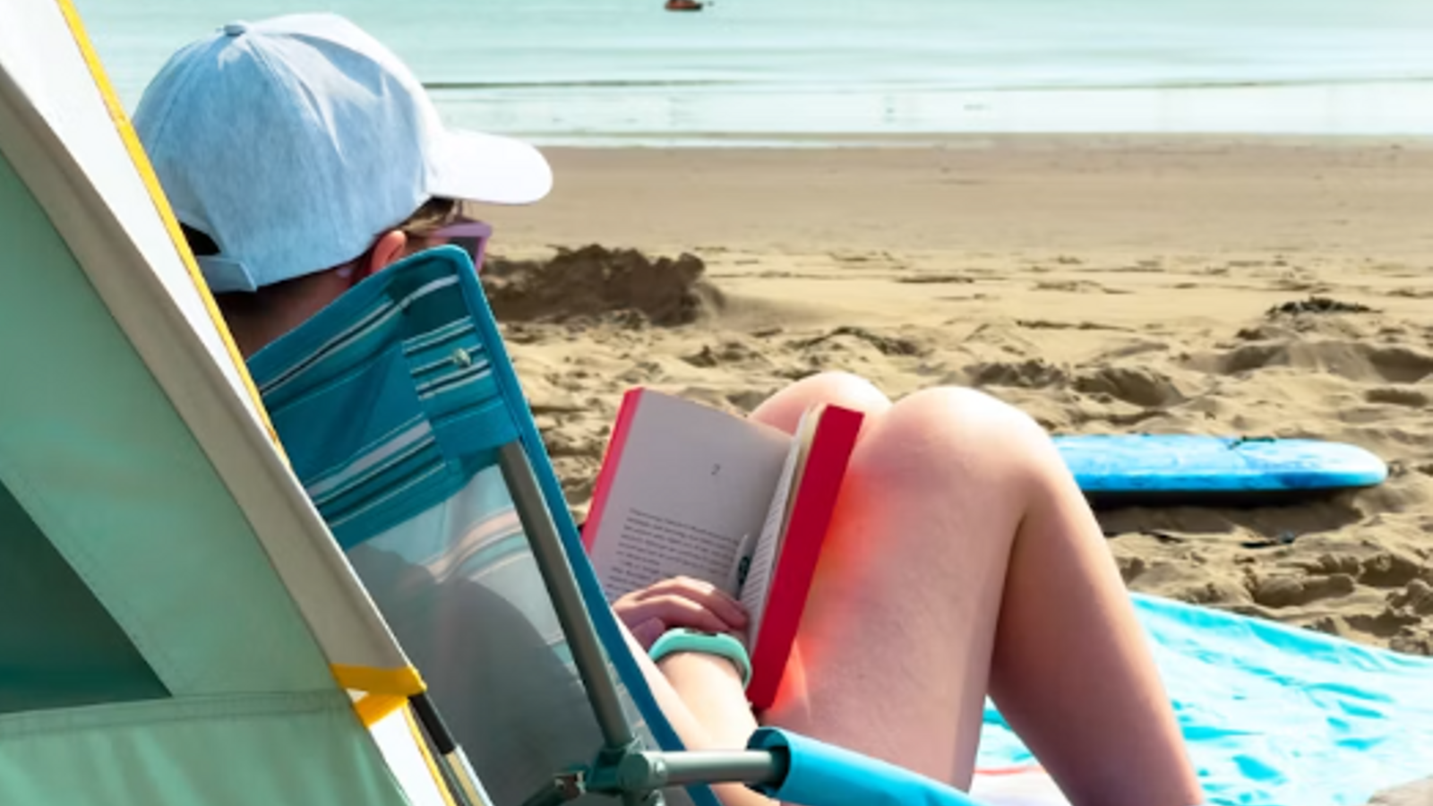Un lector aprofita la calma de la mar per desconnectar de les pantalles.