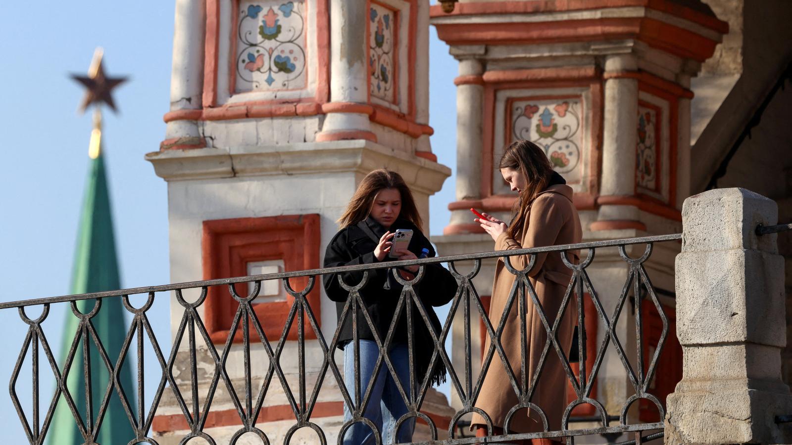 Two women use their phone in the center of Moscow.