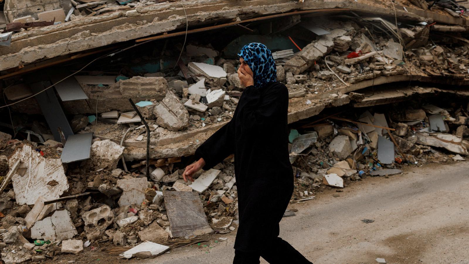 A woman walks covering her nose next to a collapsed building affected by an Israeli attack hours before the ceasefire.