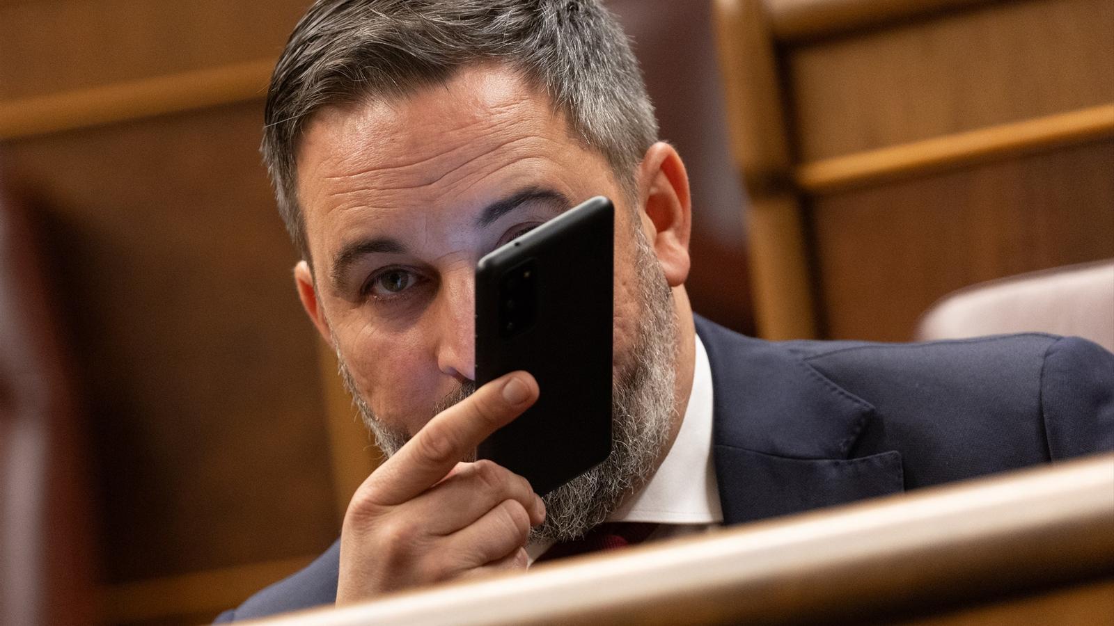 Vox leader Santiago Abascal, in the Congress chamber with a cell phone in his hand in a file image.