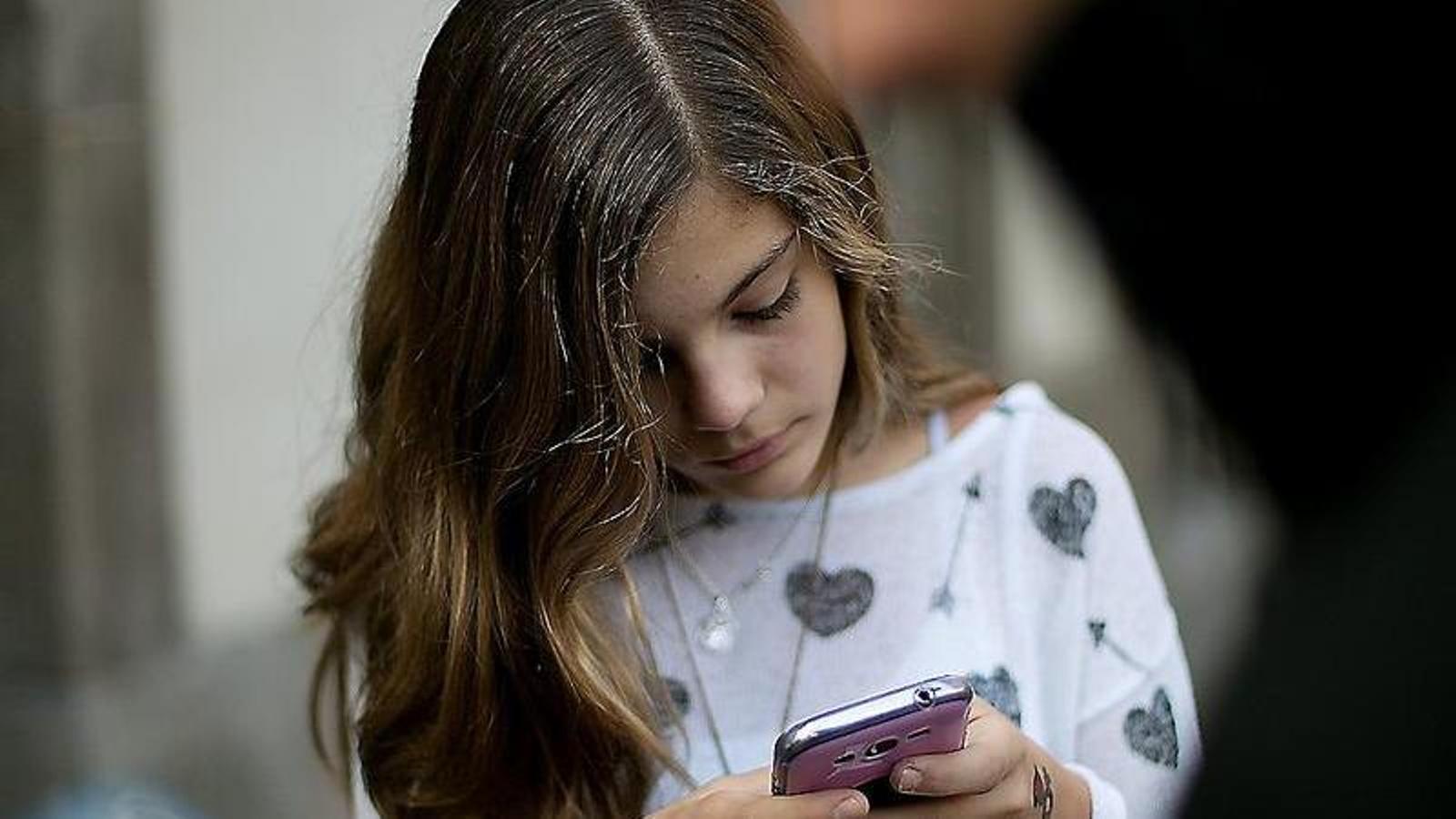 A boy and a girl glued to their cell phones. One in seven countries has introduced restrictions on cell phone use in school.