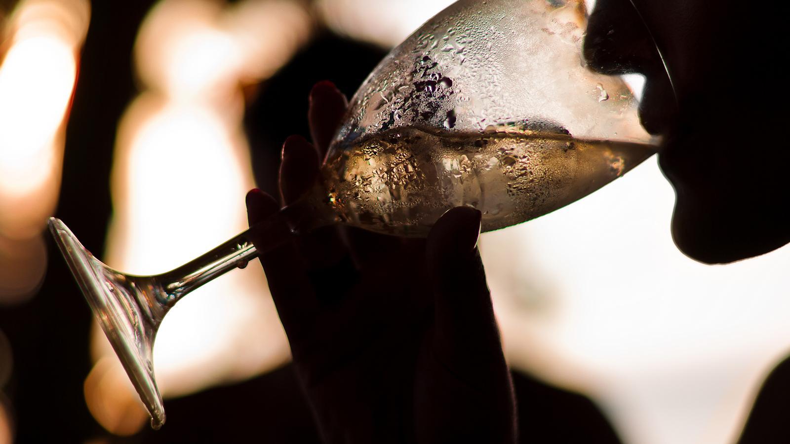 Una mujer ve vino blanco enfriado con cubitos de hielo.
