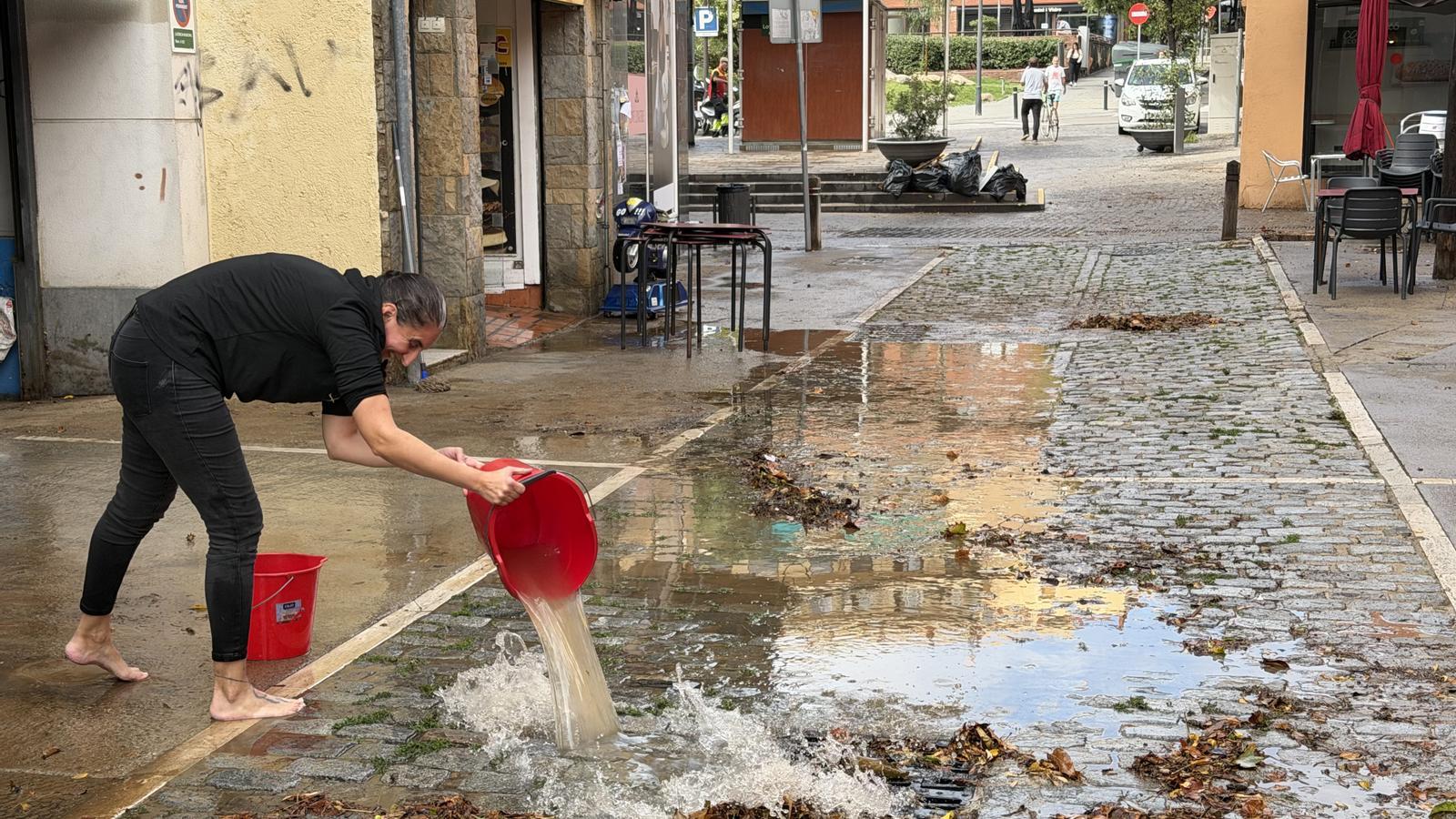 Una vecina vaciando cubos llenos de agua de la lluvia el martes