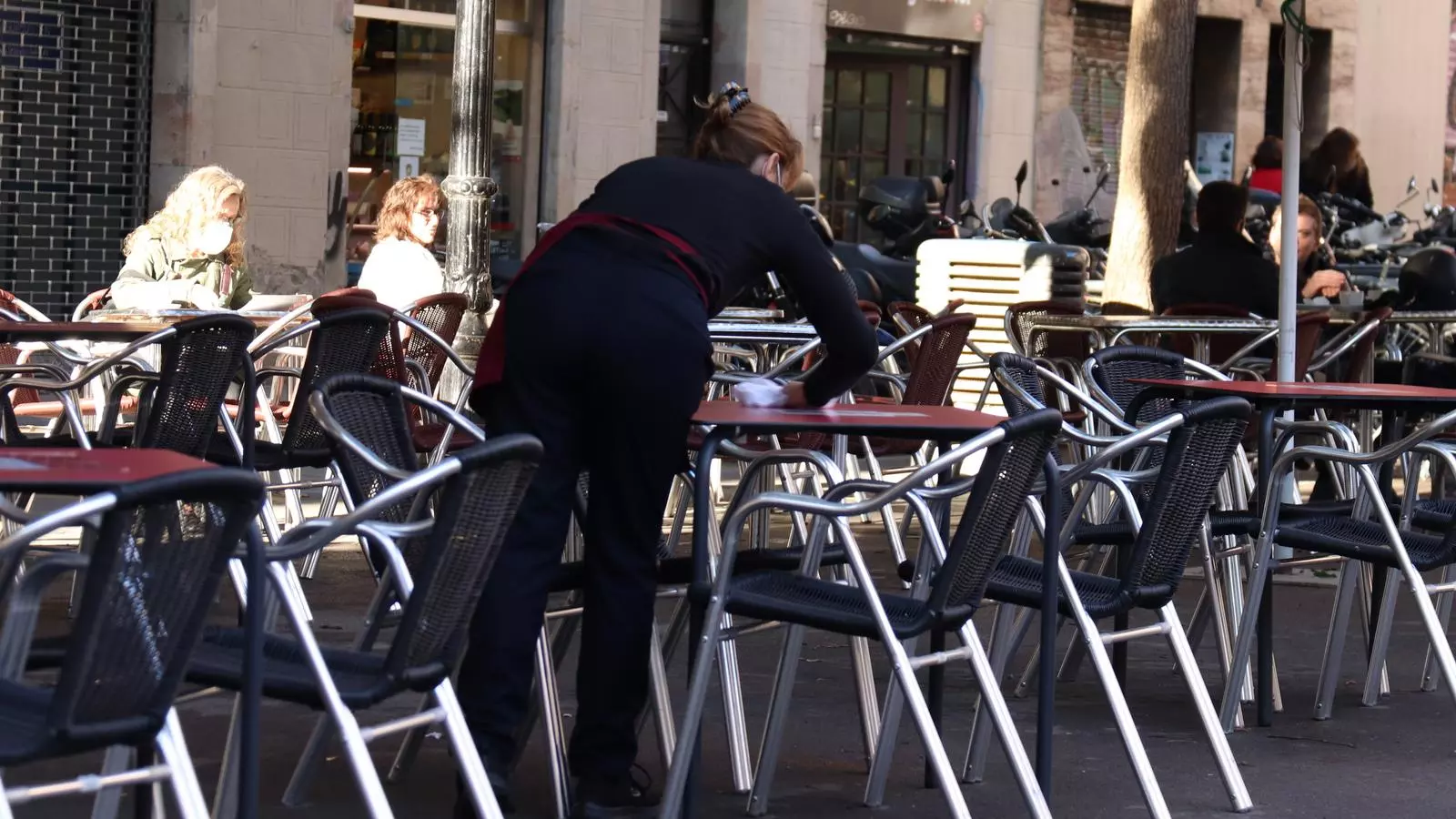 Una cambrera neteja una taula aquest dilluns al matí en una terrassa al barri de Gràcia, a Barcelona.