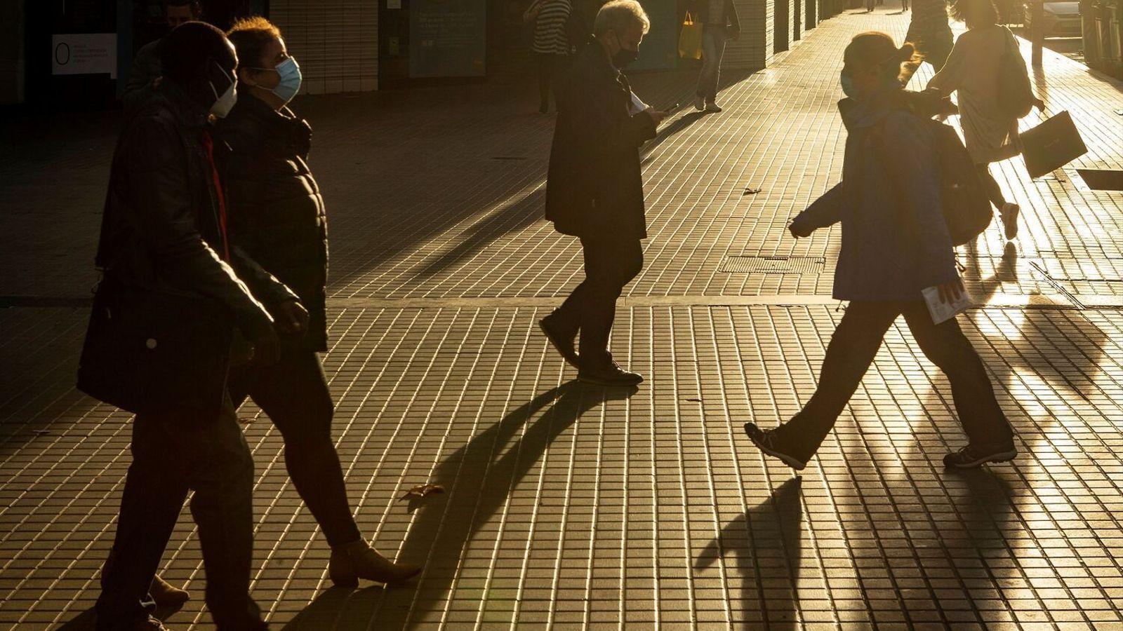 Diverses personas con mascarilla  paseante  por la calle en Barcelona