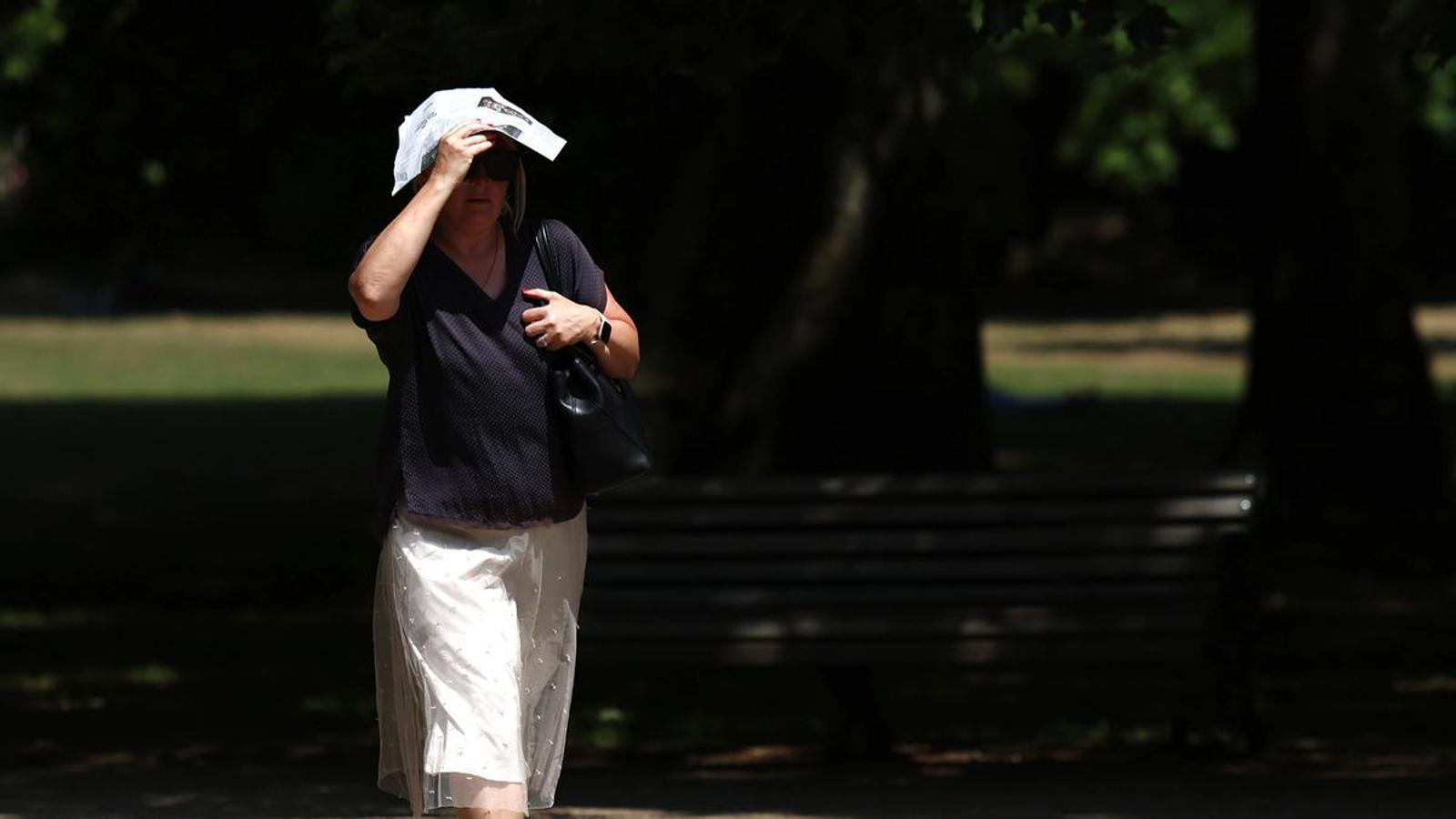A woman takes refuge under a newspaper during the heatwave in London.