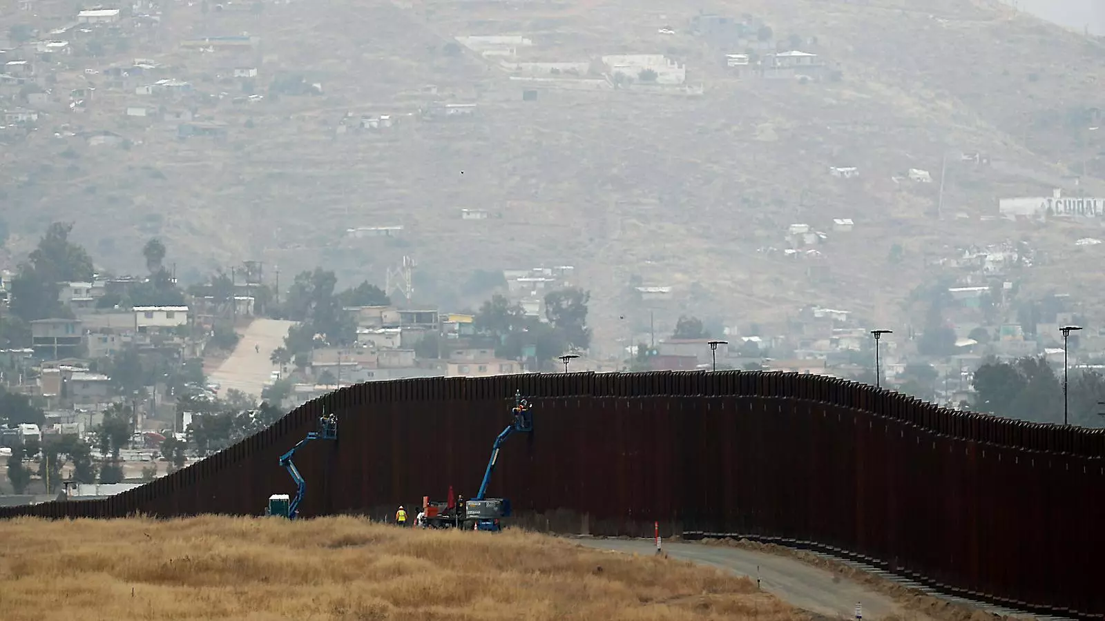 Operaris treballant en la reparació del mur que hi ha en part de la frontera entre els EUA i Mèxic.
