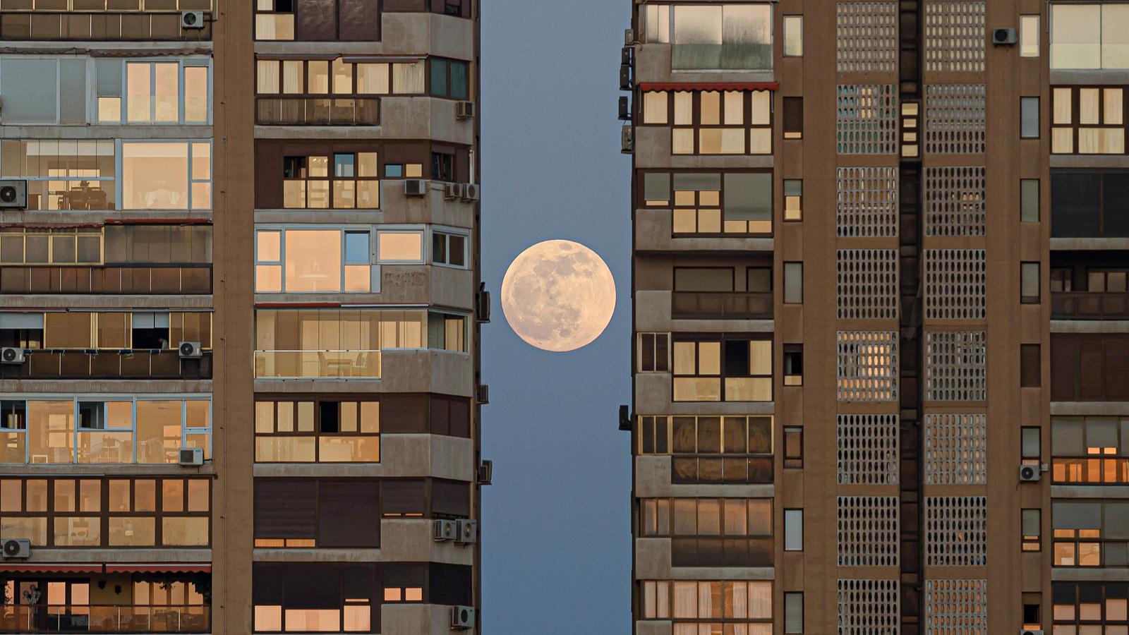 La luna sale detrás de los edificios de Málaga antes del eclipse total de Luna