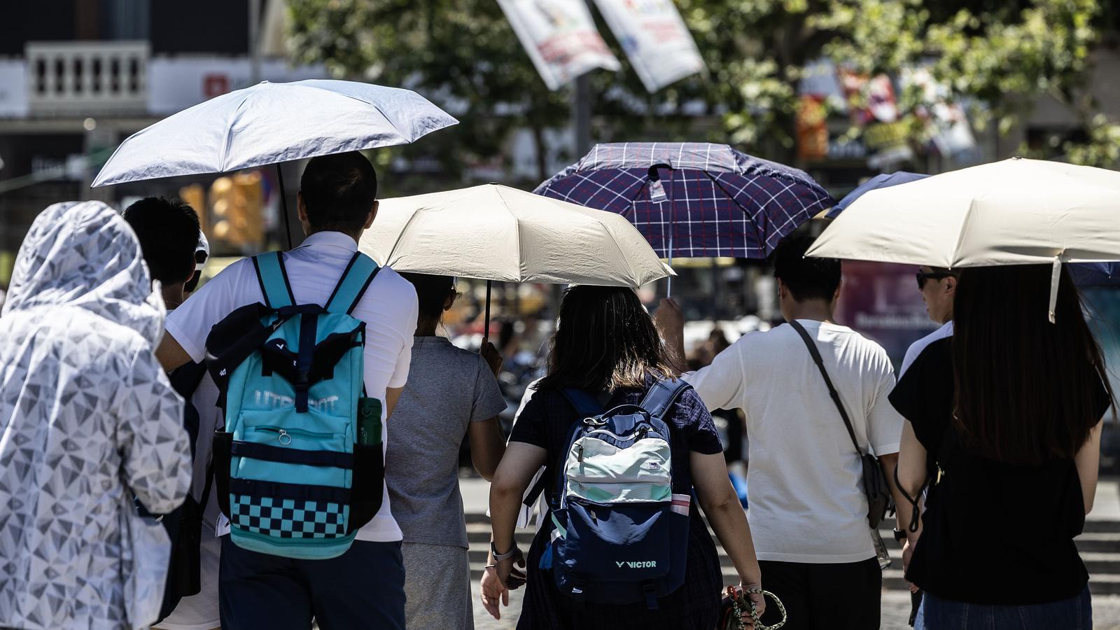 Tourists with umbrellas to protect themselves from the sun in Barcelona's Plaza de Catalunya.