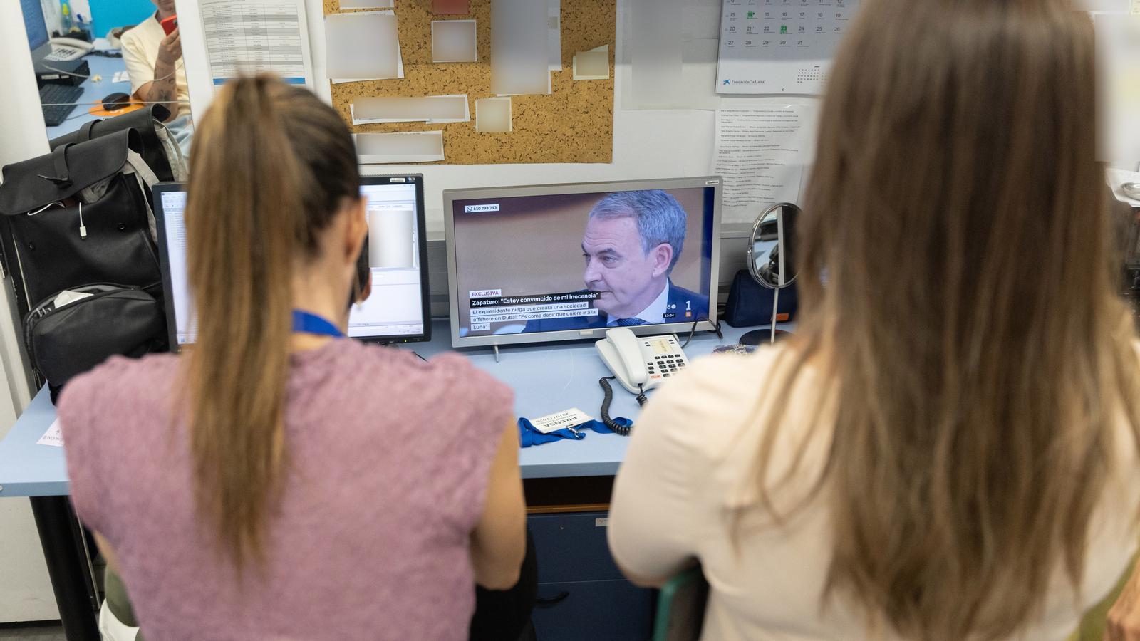 Two journalists watch Zapatero's interview in the TVE Mañaneros studio.