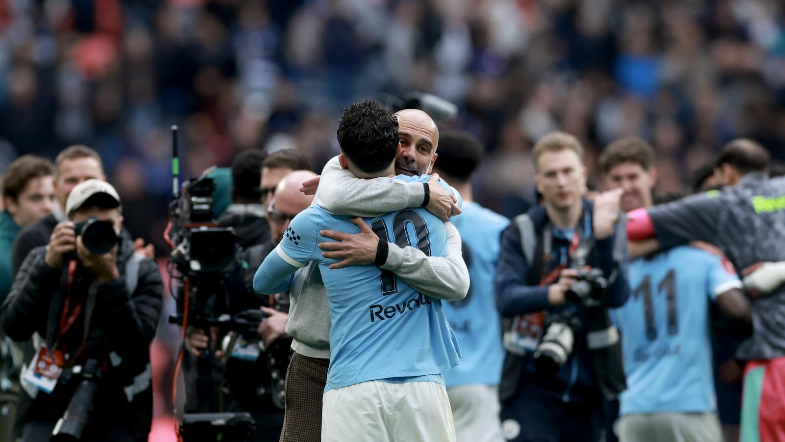 Pep Guardiola, coach of Manchester City, embracing Rayan Cherki (C) after winning the FA Cup