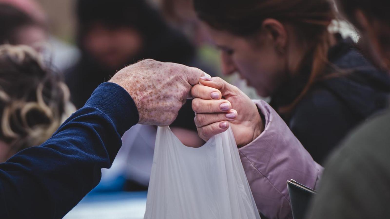 Una senyora gran rep una bossa amb menjar d'una de les cooperants.