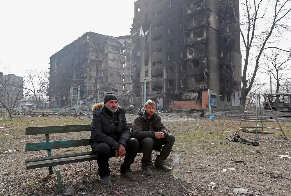 Dos residents de Mariúpol seuen davant d'edificis destrossats per l'exèrcit rus, el passat 25 de març.