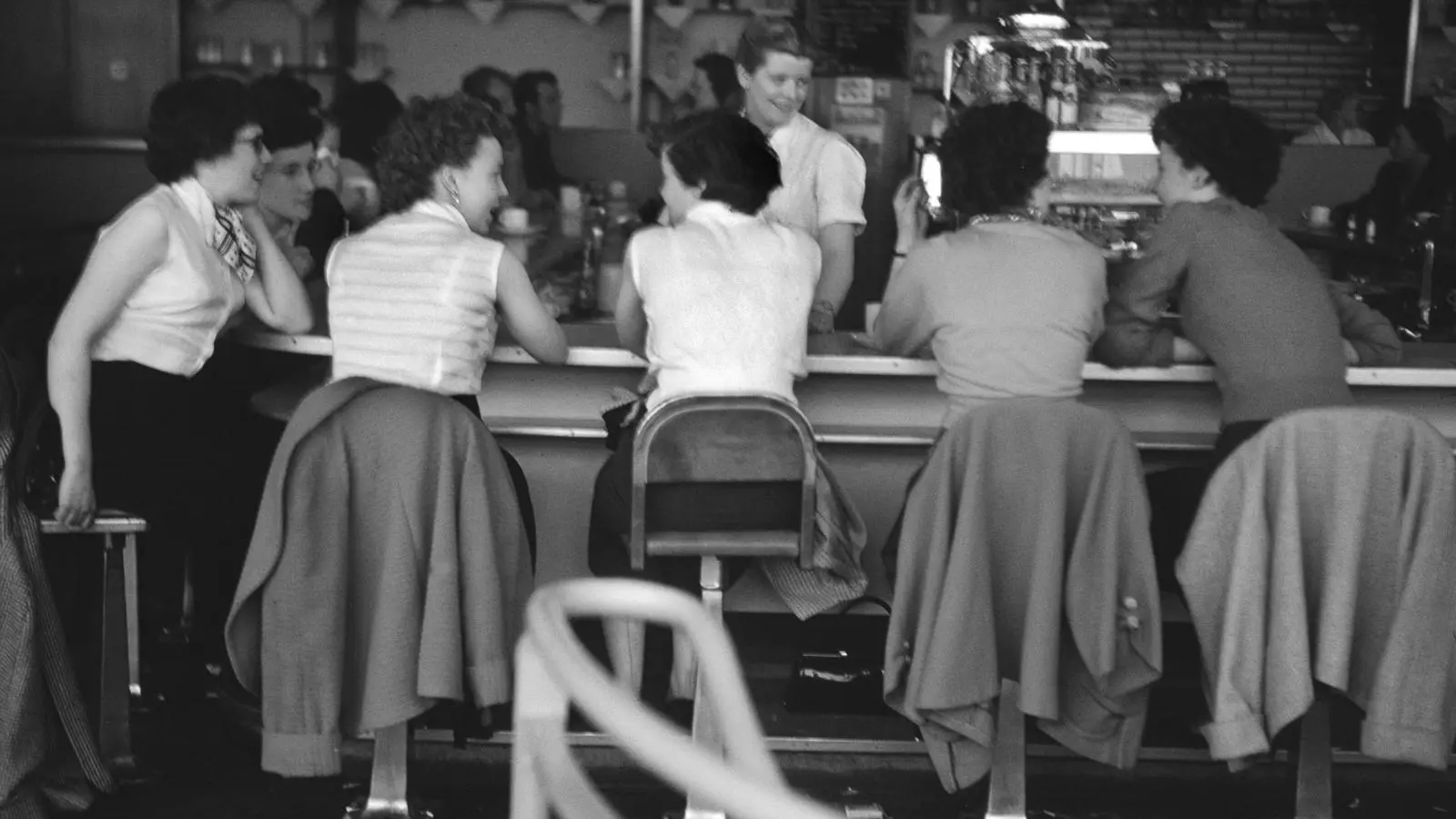 Un grup de dones conversen a la barra d'un bar.