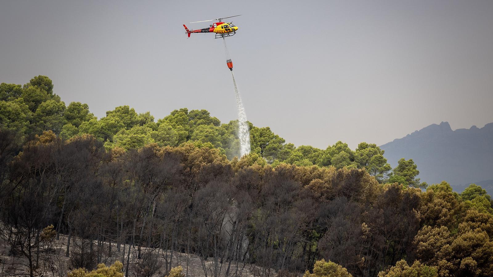 The helicopter of the Firefighters wetting the Collserola area affected by a fire declared on Tuesday next to Torre Baró.