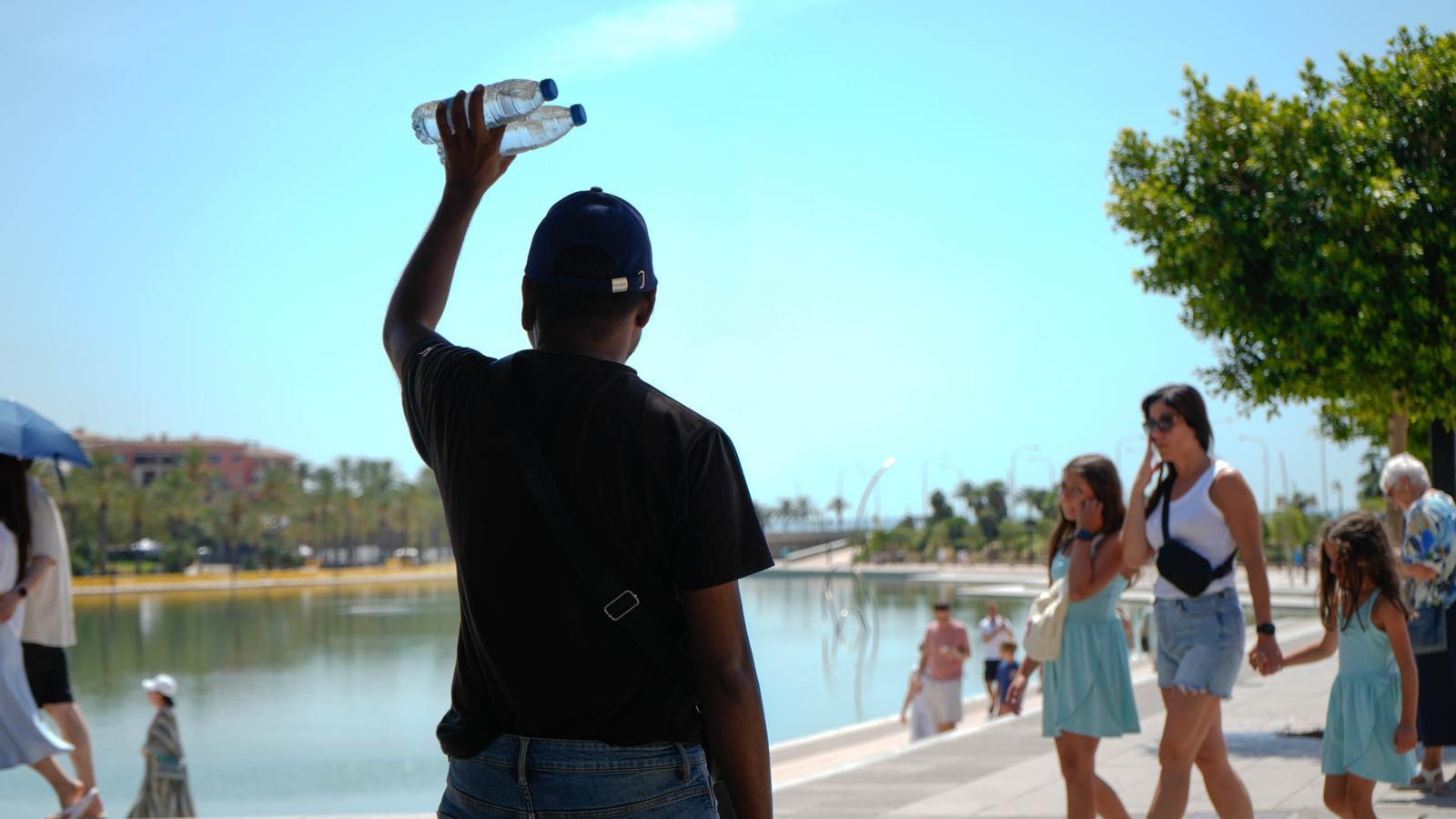 A person lifts two water bottles in the Parc de la Mar in Palma.