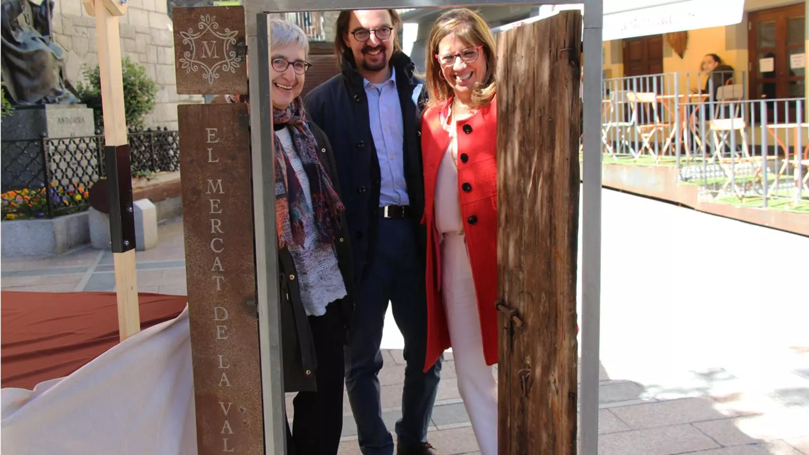 La presidenta de l'Associació de comerciants del Centre Històric d'Andorra la Vella, Anna Riberaygua; el director d'Agricultura, Landry Riba, i la consellera de Promoció Turística i Comercial del comú d'Andorra la Vella, Mònica Codina, amb la porta del Mercat de la Vall oberta. / L. M. (ANA)