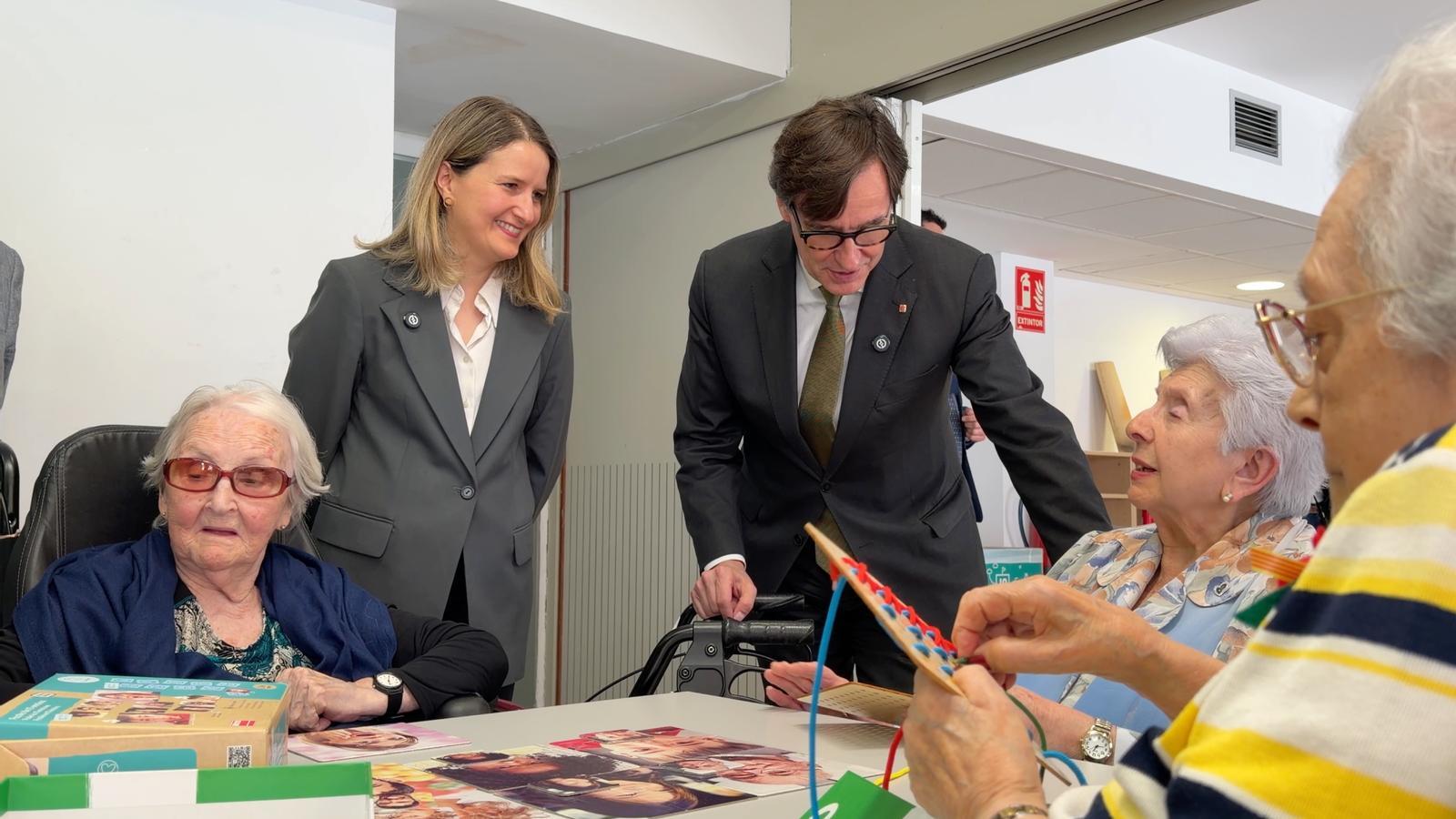 El presidente Illa y la consejera Martínez Bravo hablan animadamente con usuarios de una residencia de ancianos en Gràcia.
