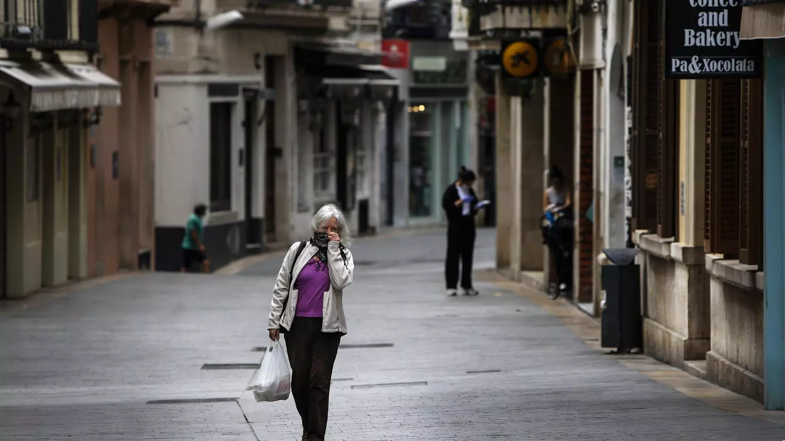 Una mujer paseante por el centro de Sitges en pleno confinamiento, cuando las oficinas bancarias eran de los pocos establecimientos que podían abrir.