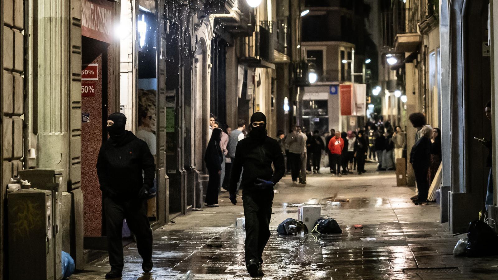 Dos jóvenes encapuchados durante la noche de los disturbios alrededor de Plaza Cataluña.
