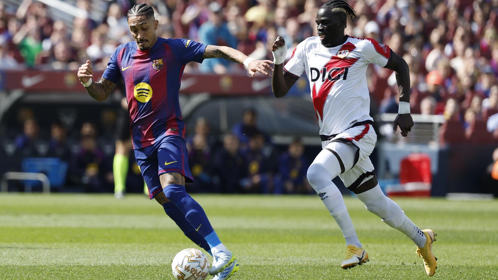 Raphinha, from FC Barcelona, and Pathé Ciss, from Rayo Vallecano, fight for the ball during the League match at Camp Nou.