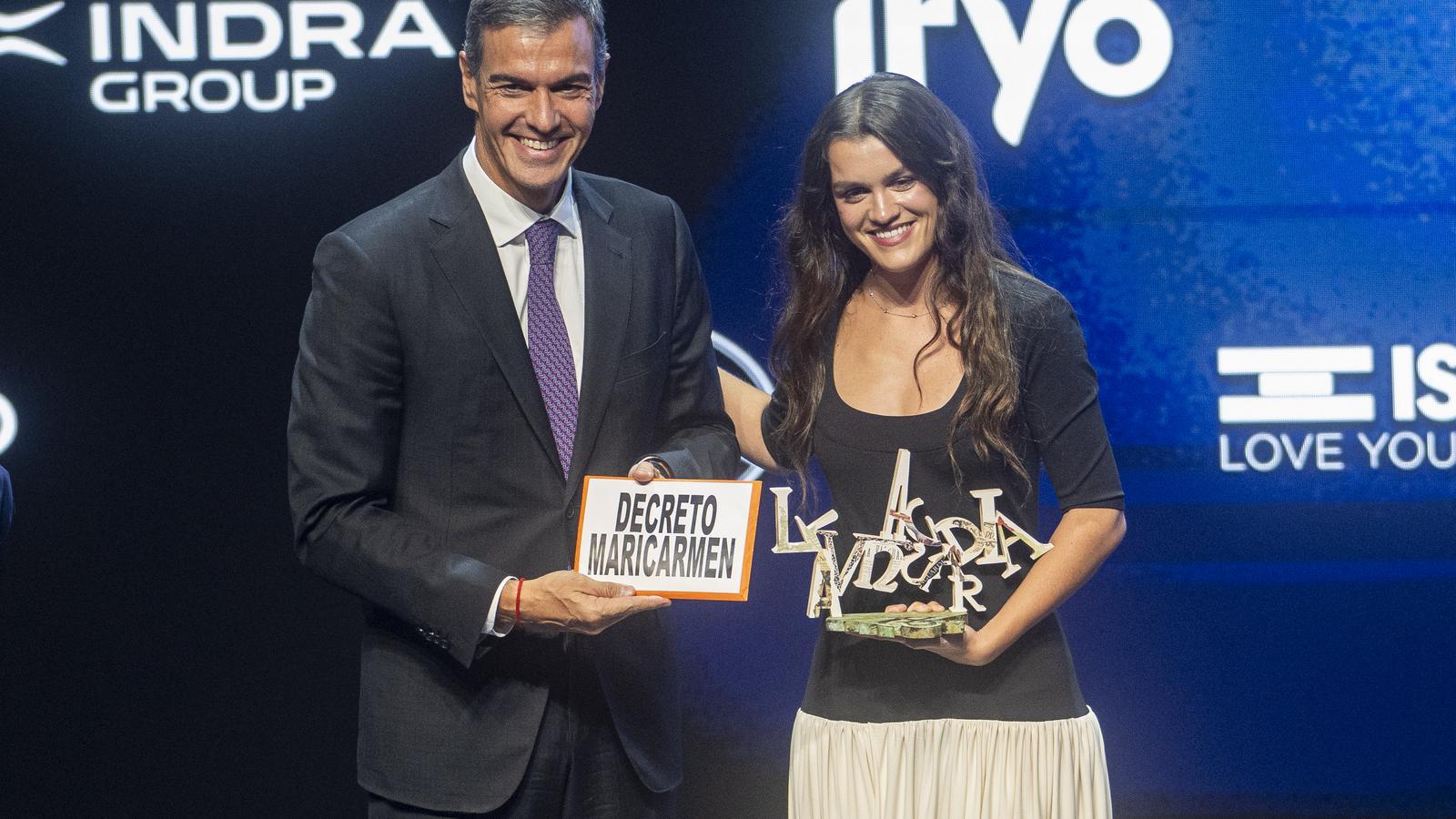 Amaia Romero handing Pedro Sánchez a poster with the message "Decreto Maricamen"