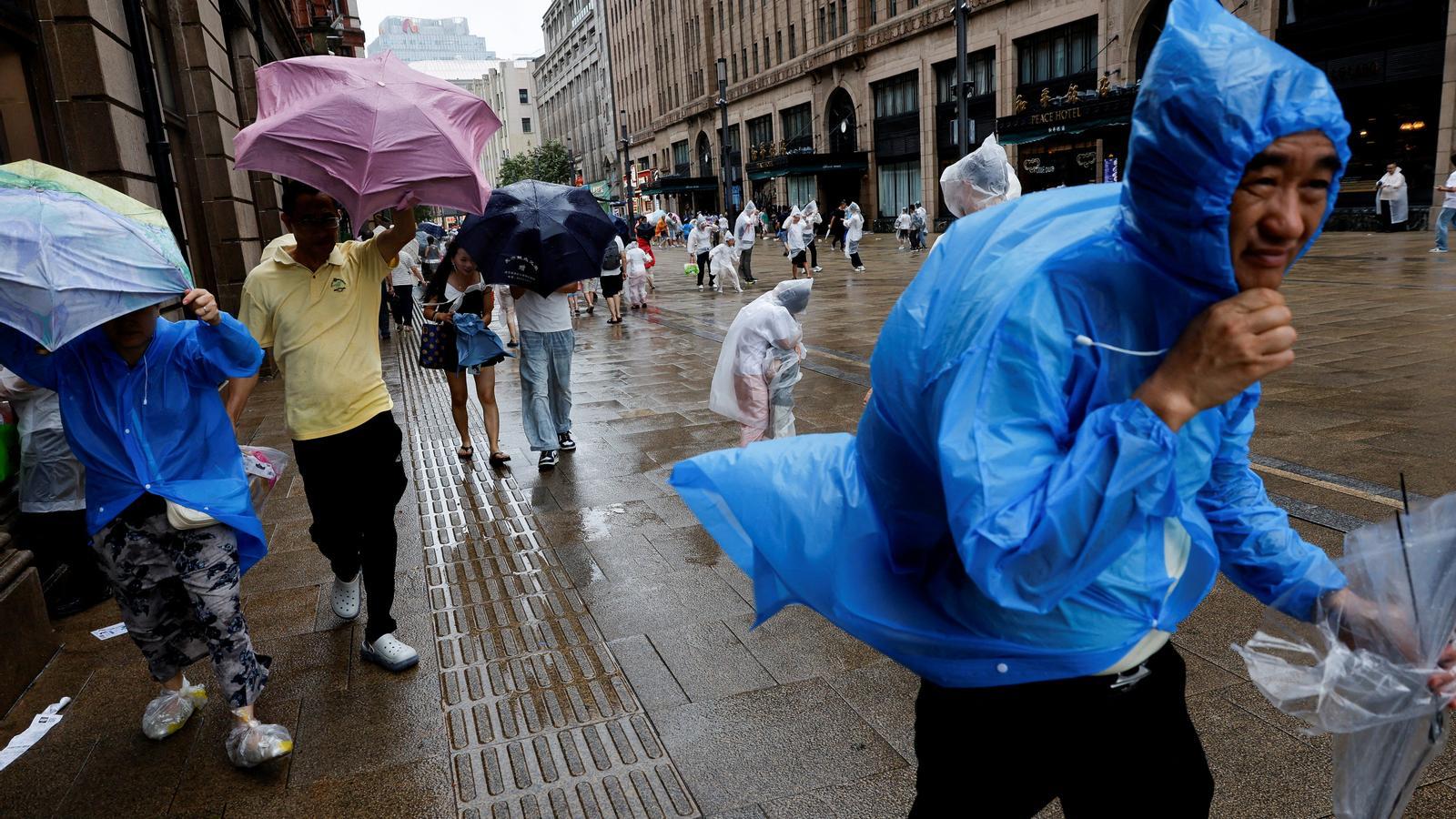 People use umbrellas and raincoats as the wind intensifies ahead of Typhoon Dolphin's arrival in Shanghai, China, on August 9