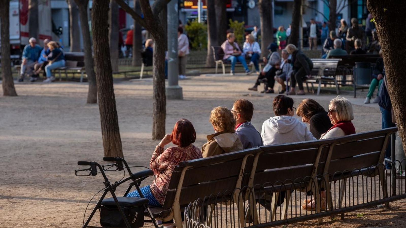 A woman rests on a bench with her walker, in a park in Cornellà de Llobregat.