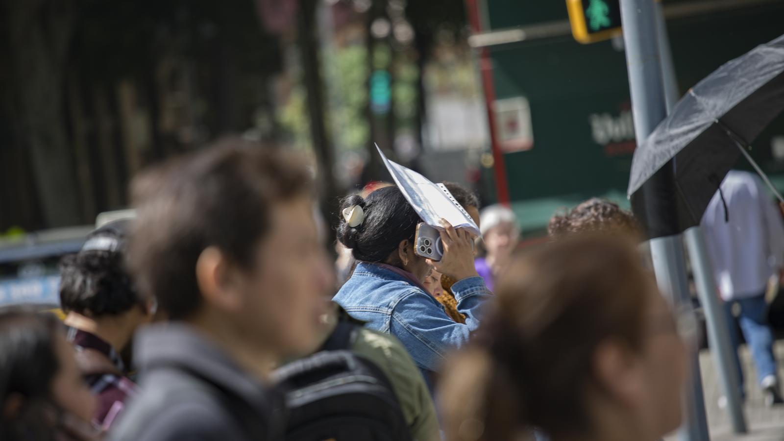 Una mujer migrante habla por teléfono mientras espera ser atendida por una entidad para la regularización.