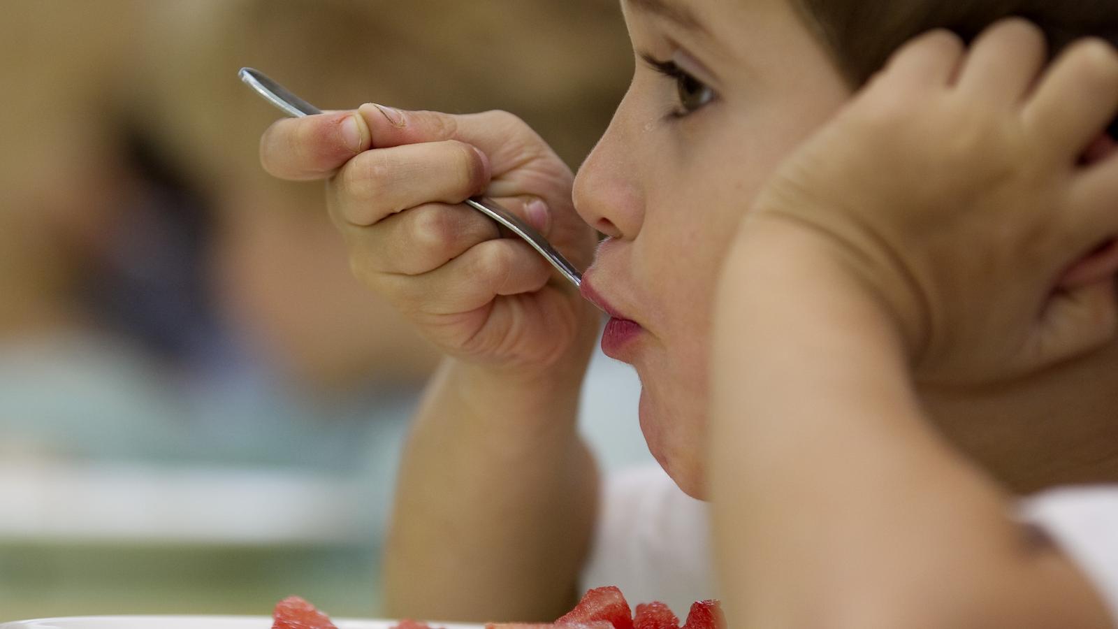 A child eating fruit in a school, in a stock image.