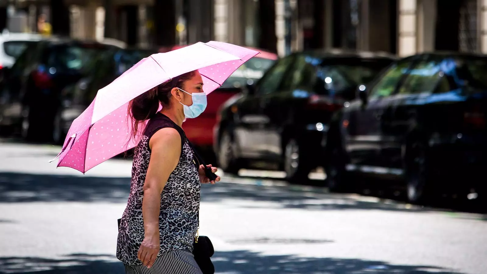 Una dona es protegeix amb un paraigües de la intensa calor, l'estiu del 2020
