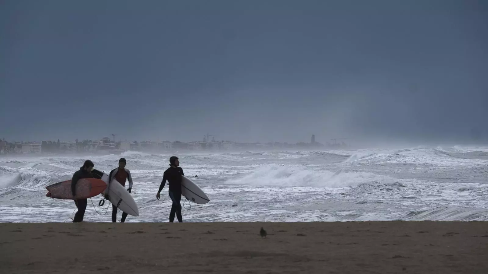 Tres surfistes aprofitant les onades del temporal, a la platja de Castelldefels
