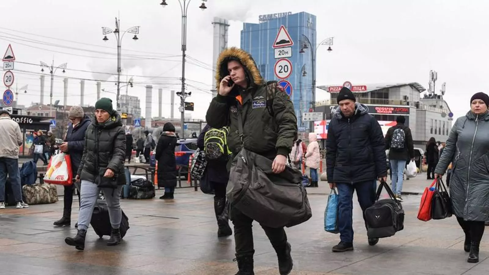 Moltes persones, algunes portant bosses i maletes, caminant cap a l'estació de tren de Kíev-Pasazhirski, a Kíev
