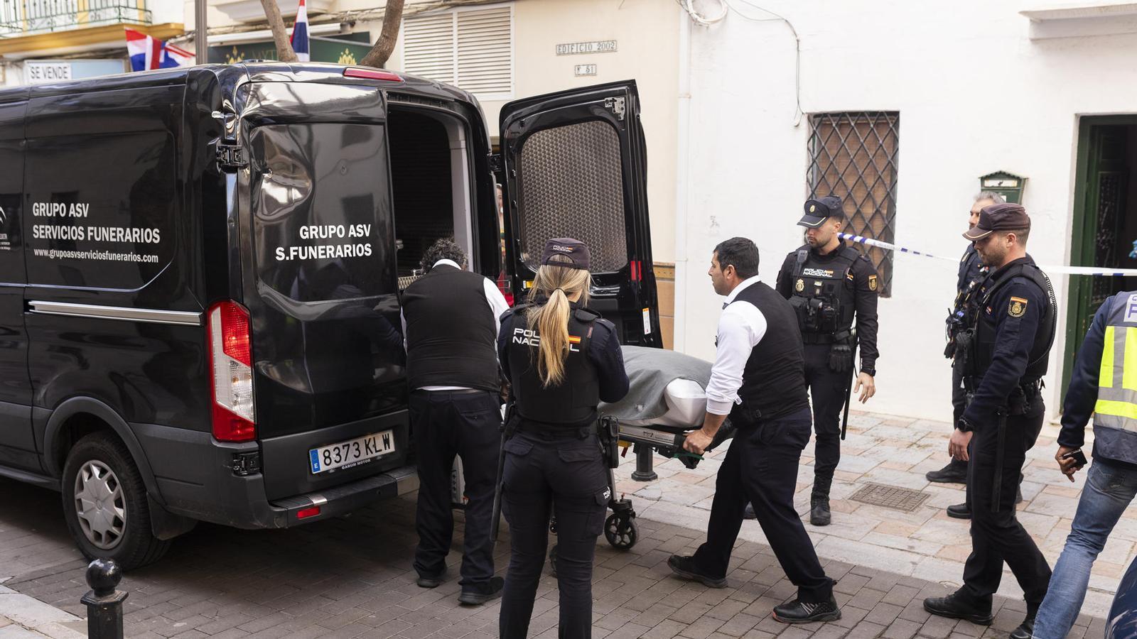 Personal de la funeraria retiran uno de los cuerpos frente a la presencia de policías, en Fuengirola.