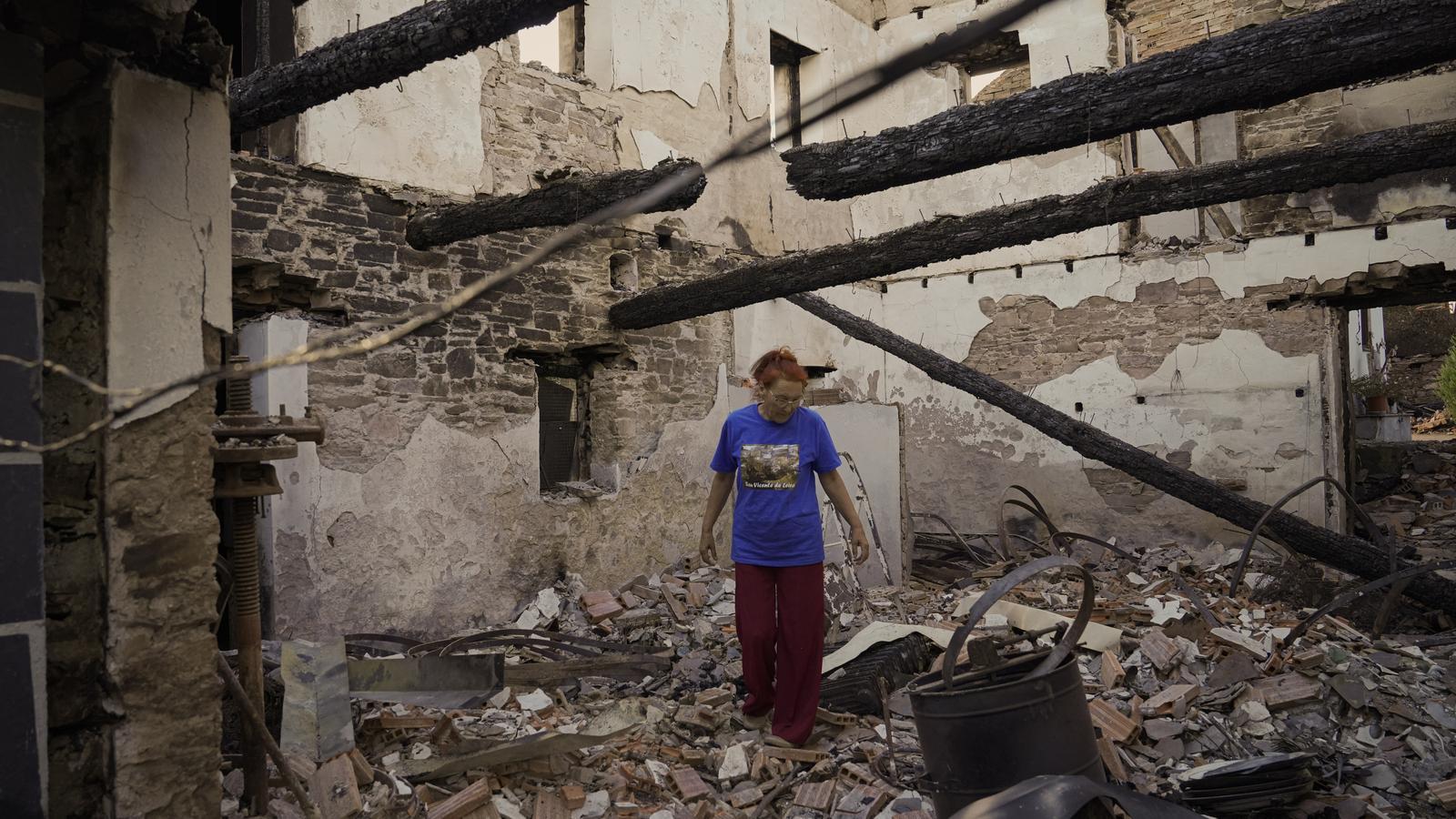 A woman watches her house destroyed by a fire.