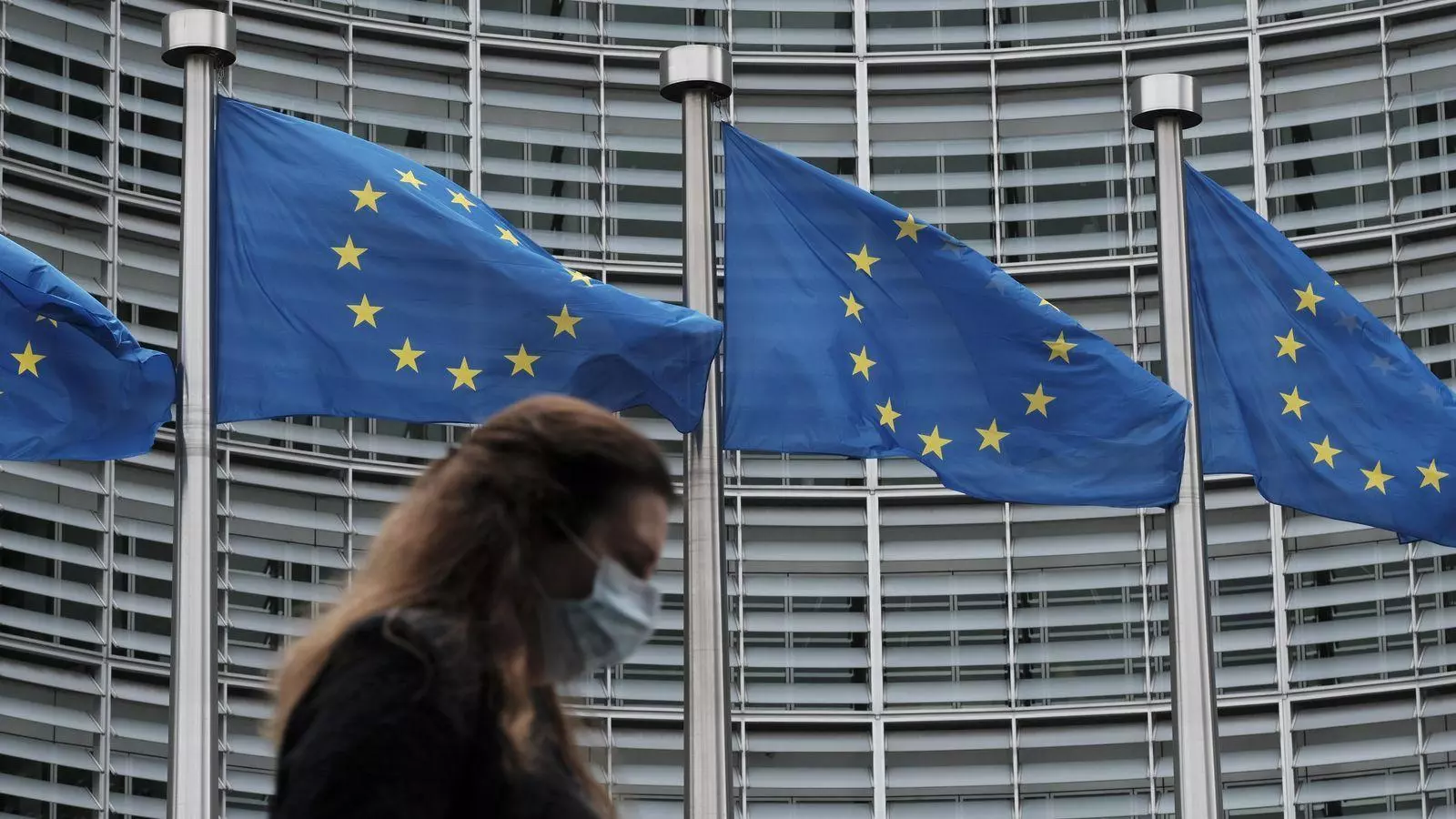 Una mujer pasa por ante las banderas de la sede de la Comisión Europea en Bruselas.