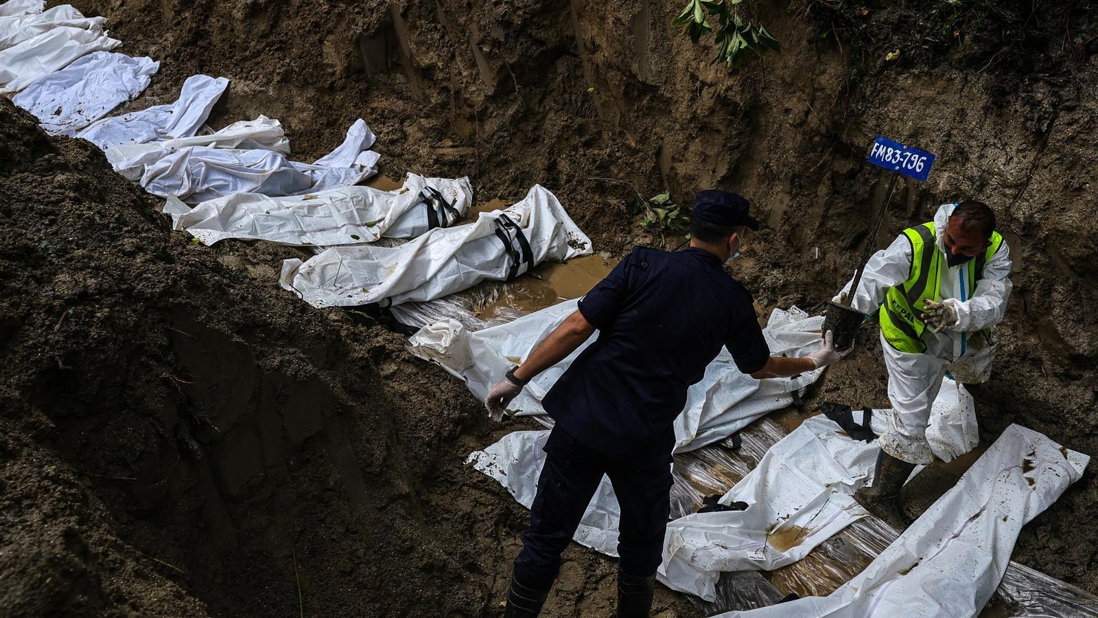 Security personnel place a tag with a victim's identification on the lifeless body in the Gokarna forest, in Kathmandu, Nepal.
