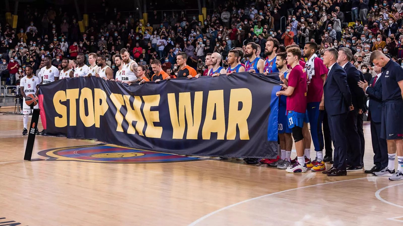Els jugadors del Barça i el Mònaco amb una pancarta contra la guerra al Palau Blaugrana.