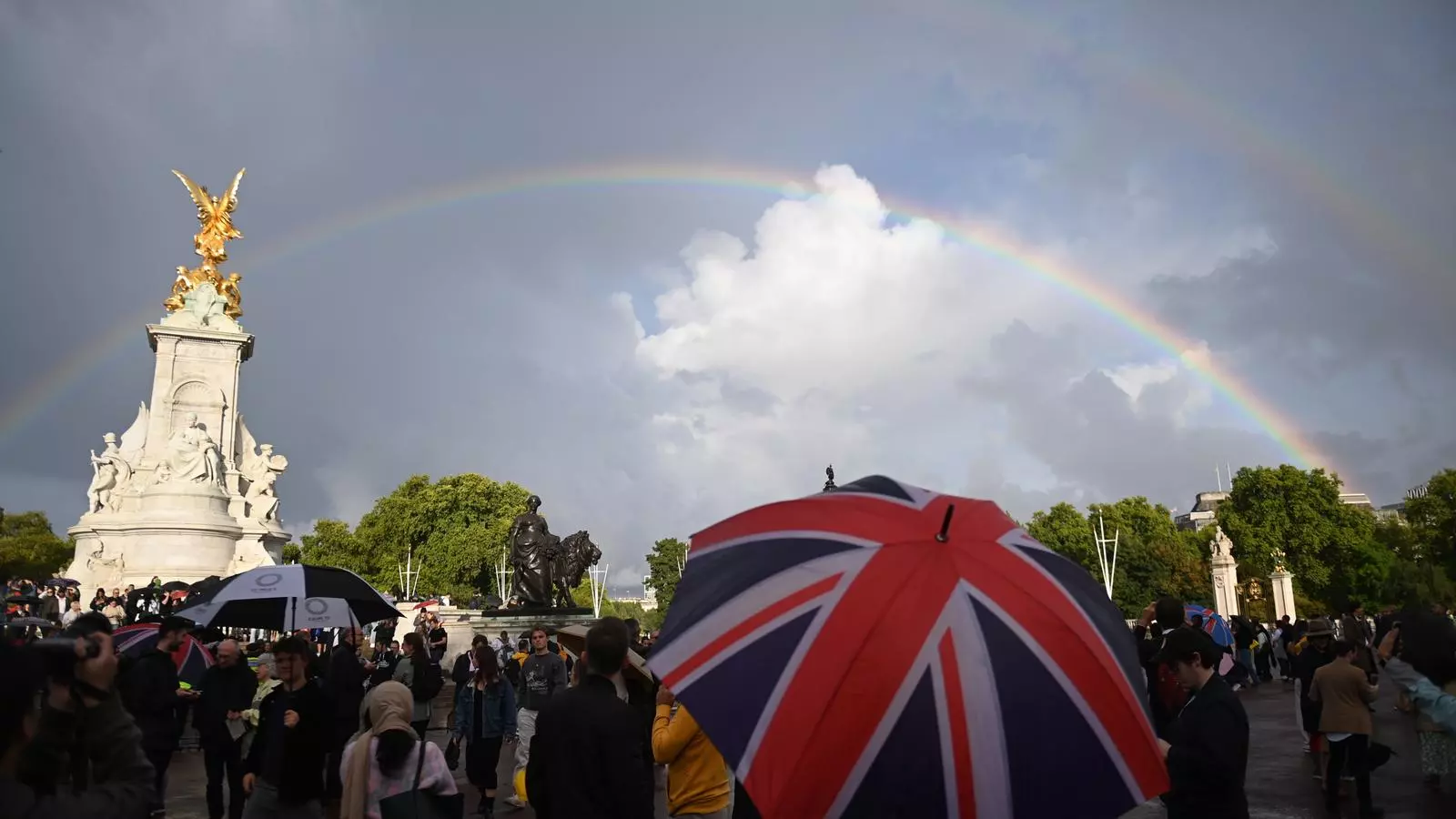 Un arc de Sant Martí apareix sobre el Memorial de la Reina Victòria mentre la gent es reuneix davant del Palau de Buckingham a Londres