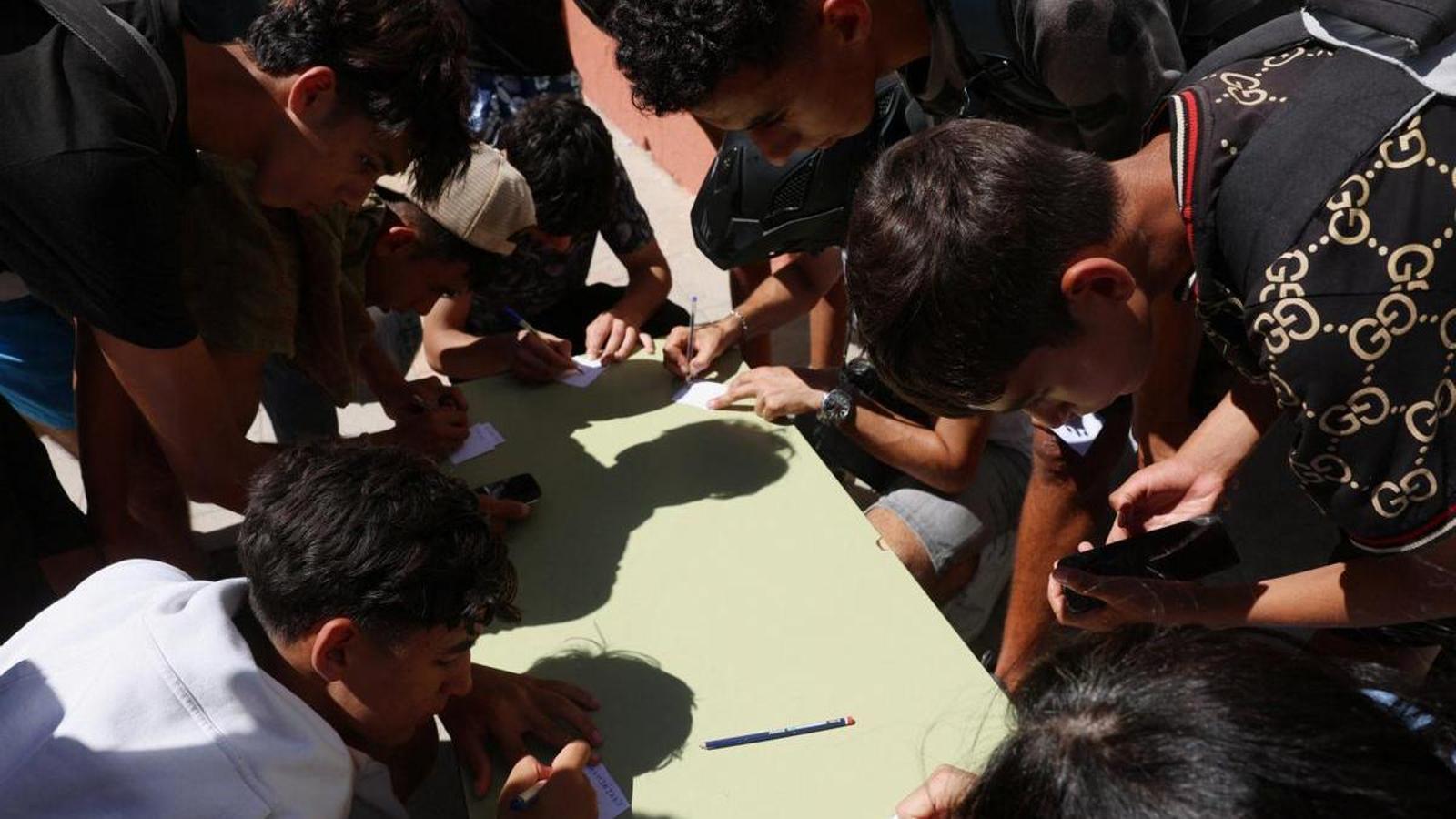 Jóvenes migrantes, algunos menores, anotan su información mientras las ONG los registran en un censo español, en Ceuta.
