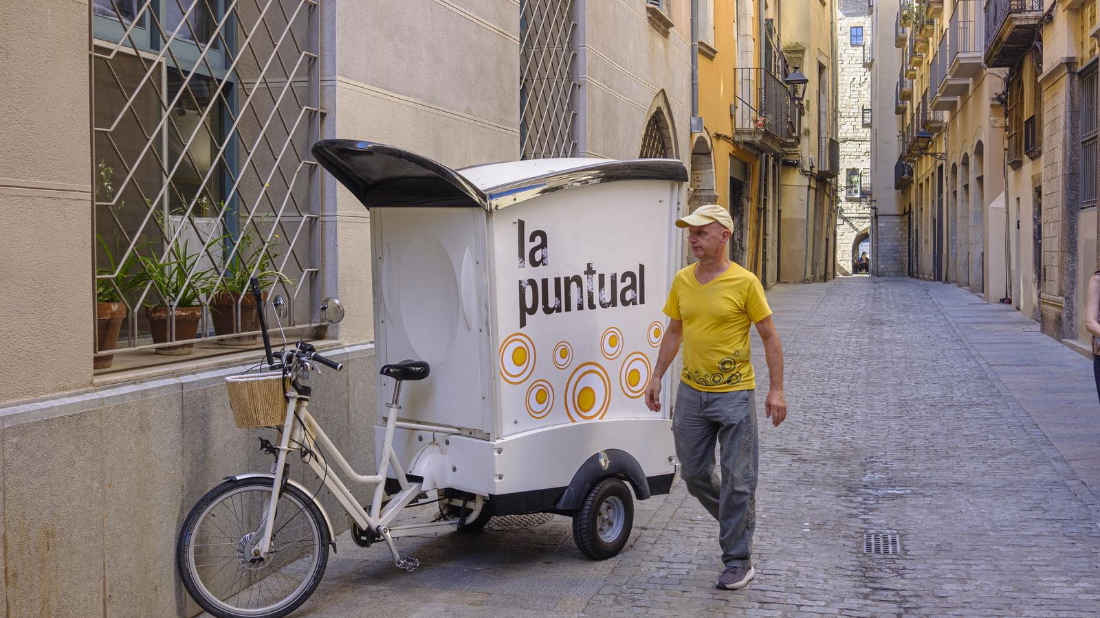 Joan Pujades, baker of La Puntual, with his tricycle delivering bread through Girona.
