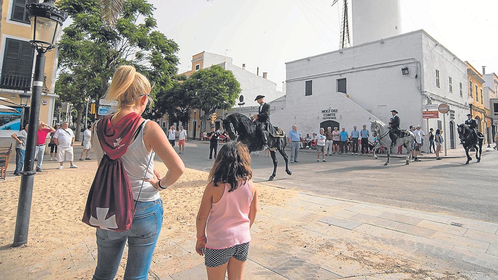 Una dona i la seva filla observen el replec del matí del dia de Sant Joan a la plaça de les Palmeres de Ciutadella.