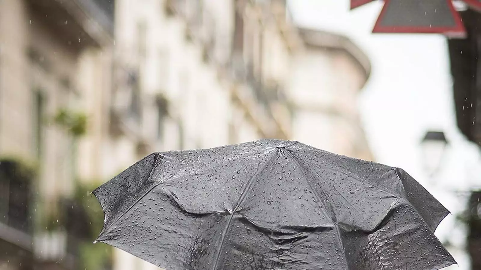 Un vianant protegint-se de la pluja amb un paraigua en un carrer del centre de Barcelona.