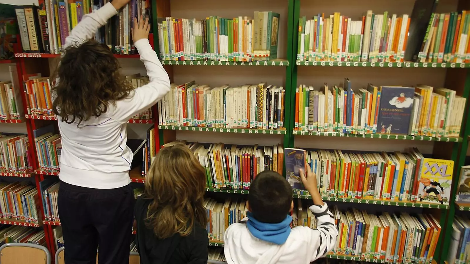 Tres nens en una biblioteca escolar