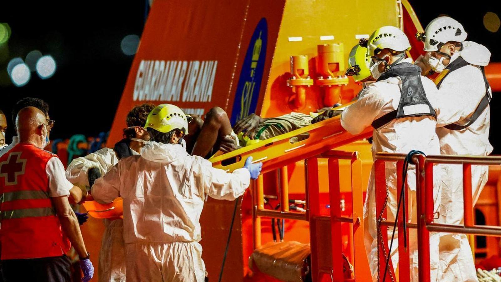 Rescue teams help a migrant to enter the Spanish coast guard ship at the port of Arguineguín, on the island of Gran Canaria